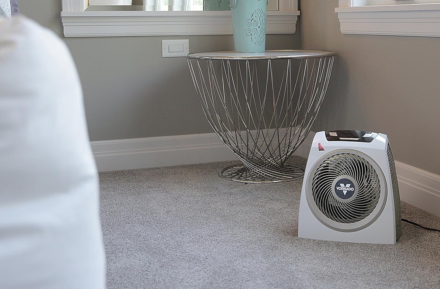 a vornado space heater sits on a carpeted floor in a brightly lit bedroom with natural light