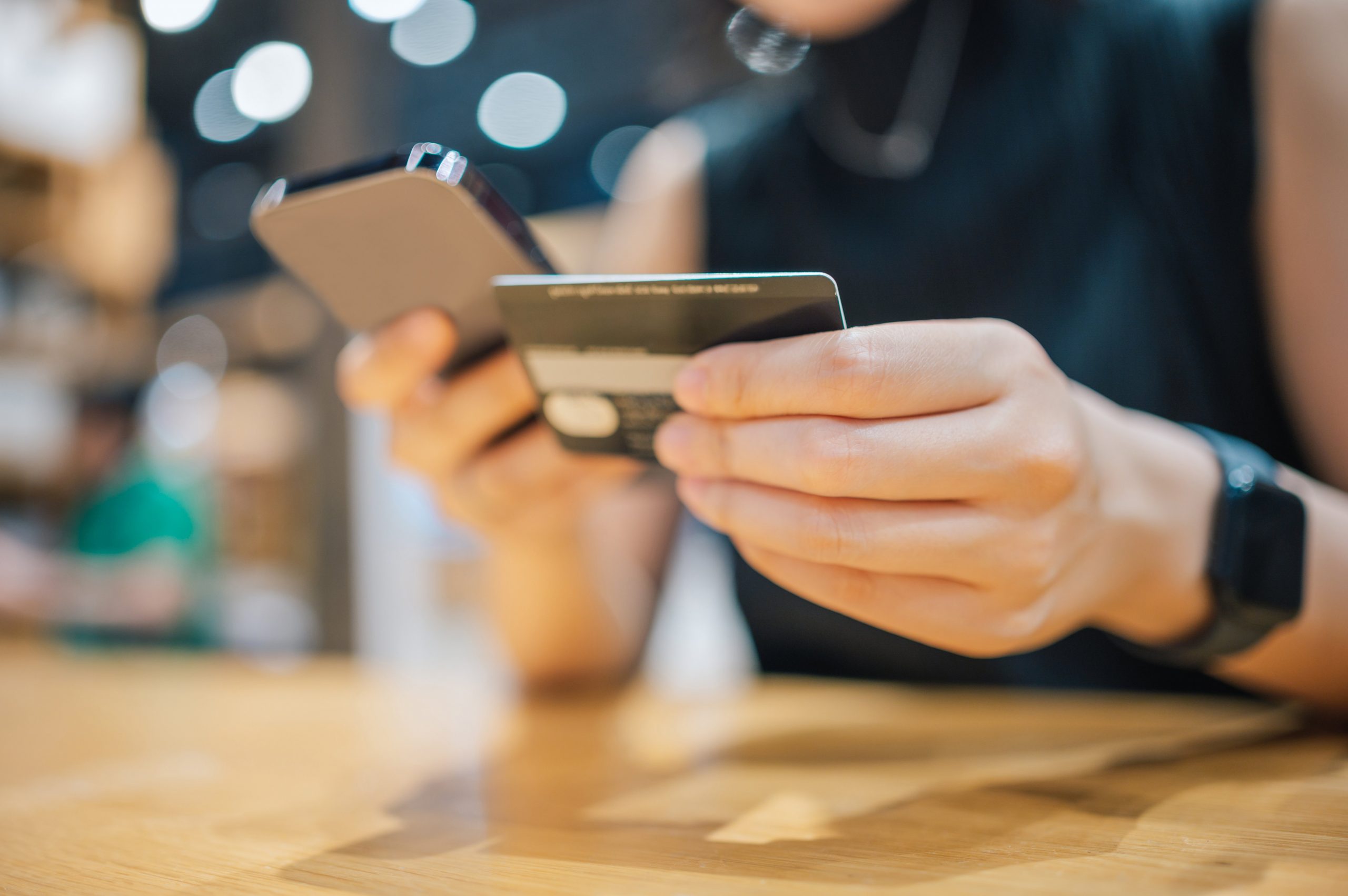 A person holds a phone in one hand and a credit card in another.