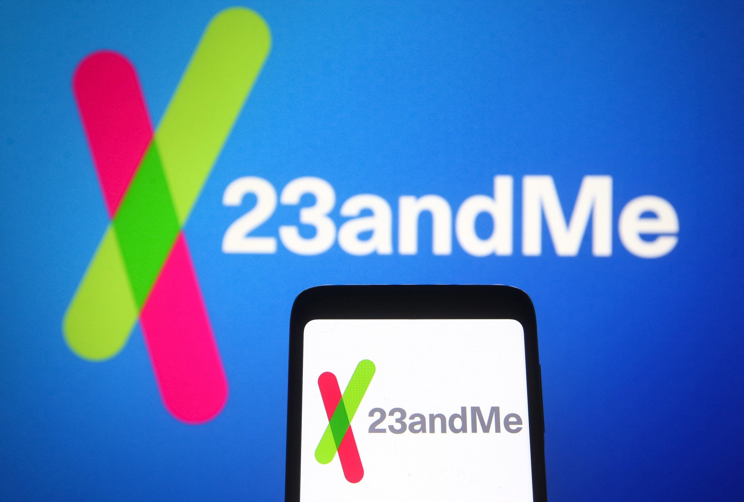 23andme logo on a phone in front of a blue background with the same logo