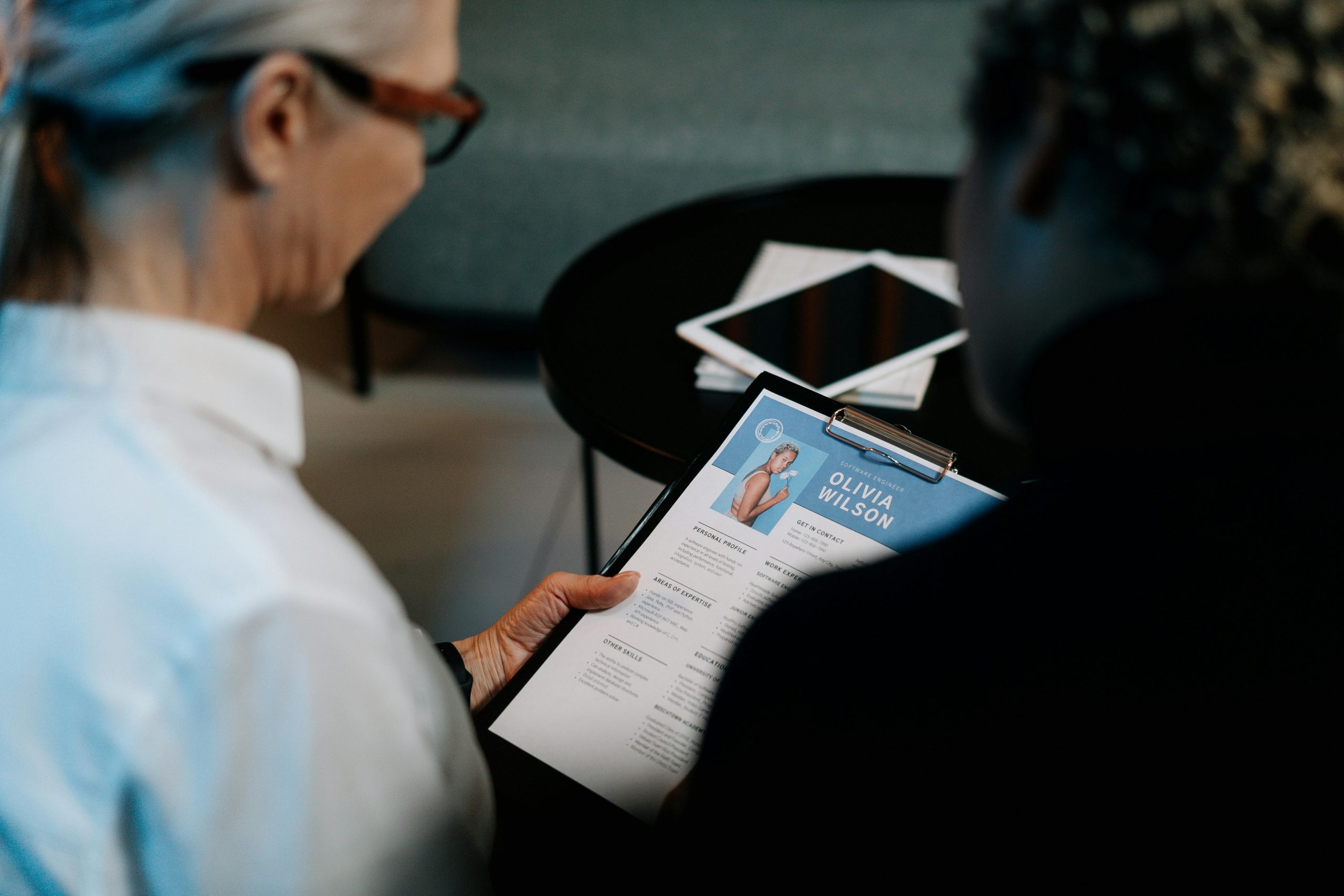 older woman in glasses reviewing a woman's CV