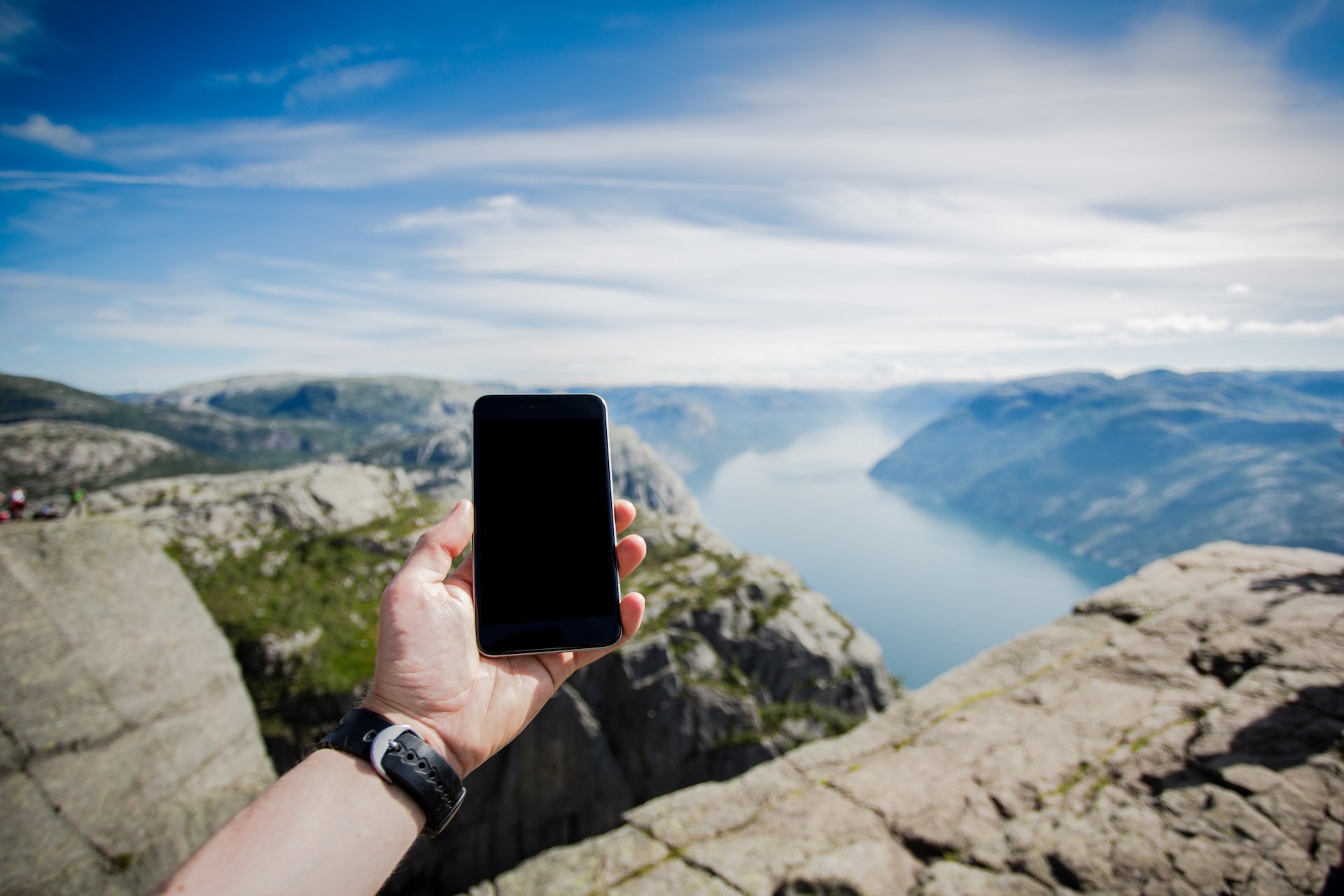 A person holds a phone up toward the horizon in a remote area.