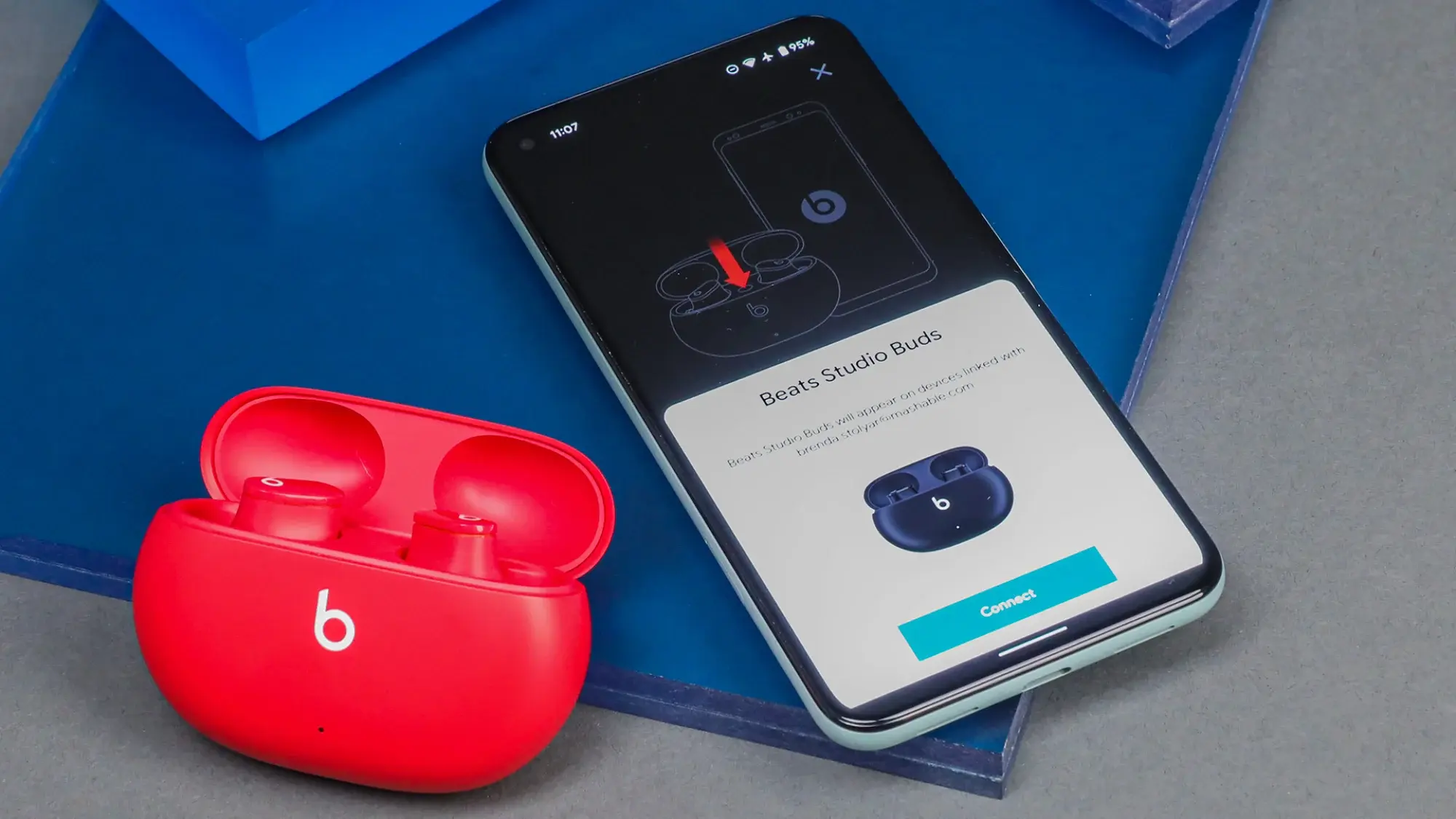 A pair of Beats Studio Buds on a table next to a phone