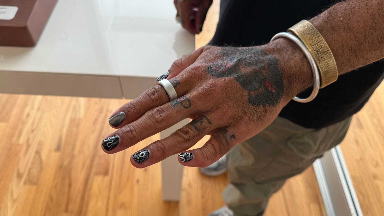 Oura Ring 4 on a man's finger on a tatooed hand