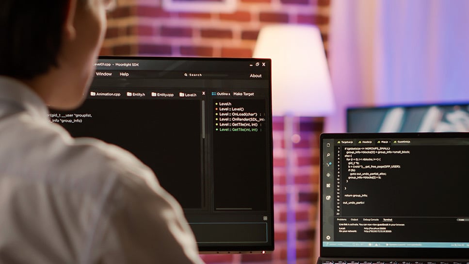 man coding on two computer screens