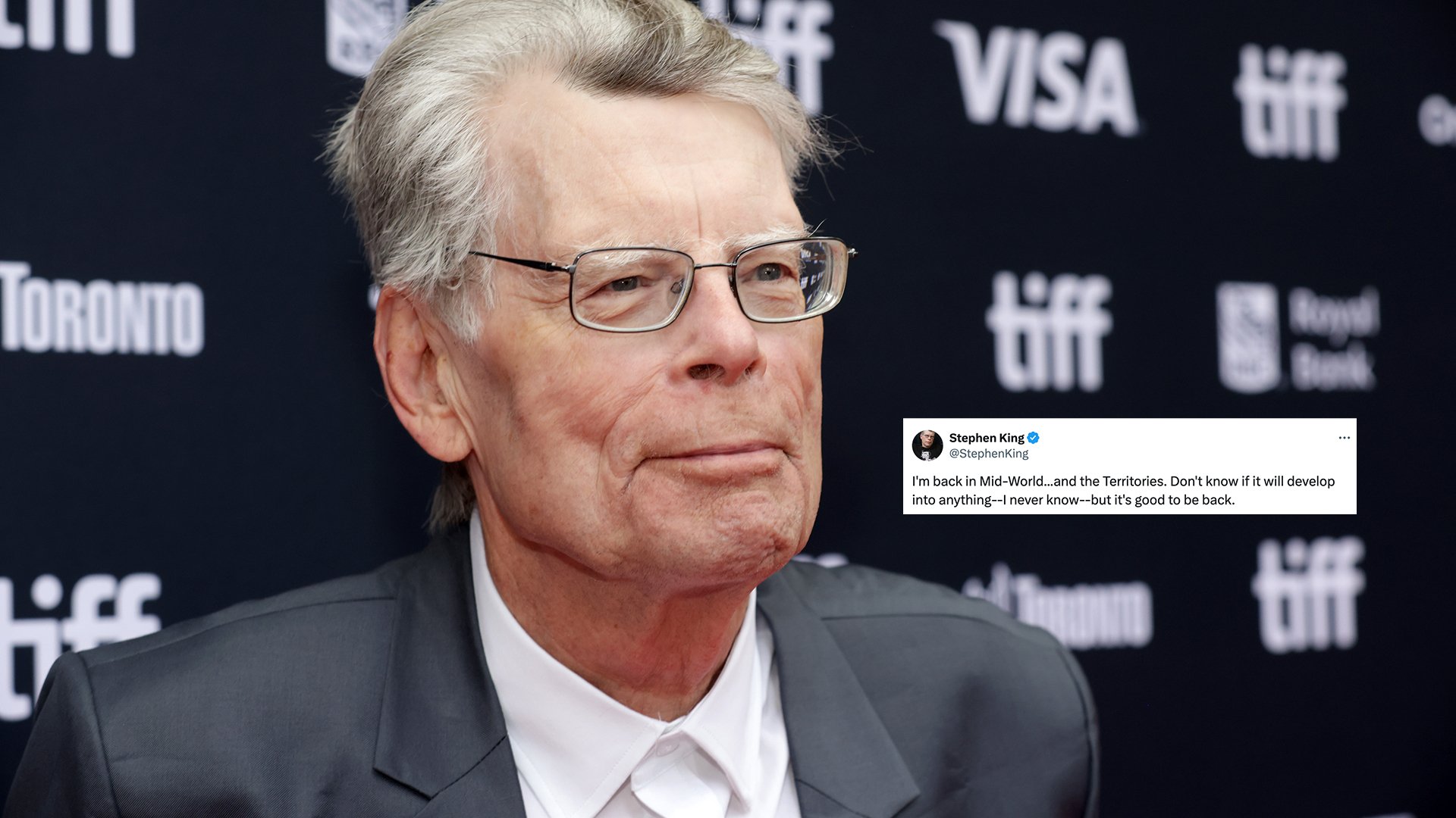 A man in a suit stands on the red carpet.