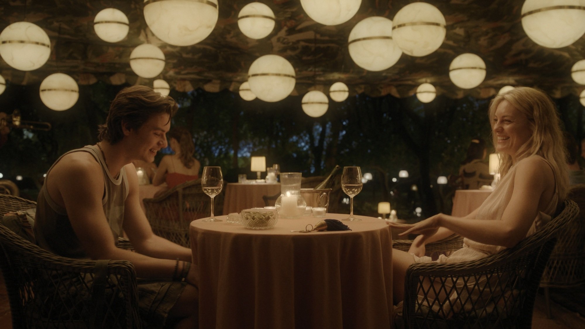 Louis Partridge and Leila George eat at an outdoor restaurant in "Disclaimer."