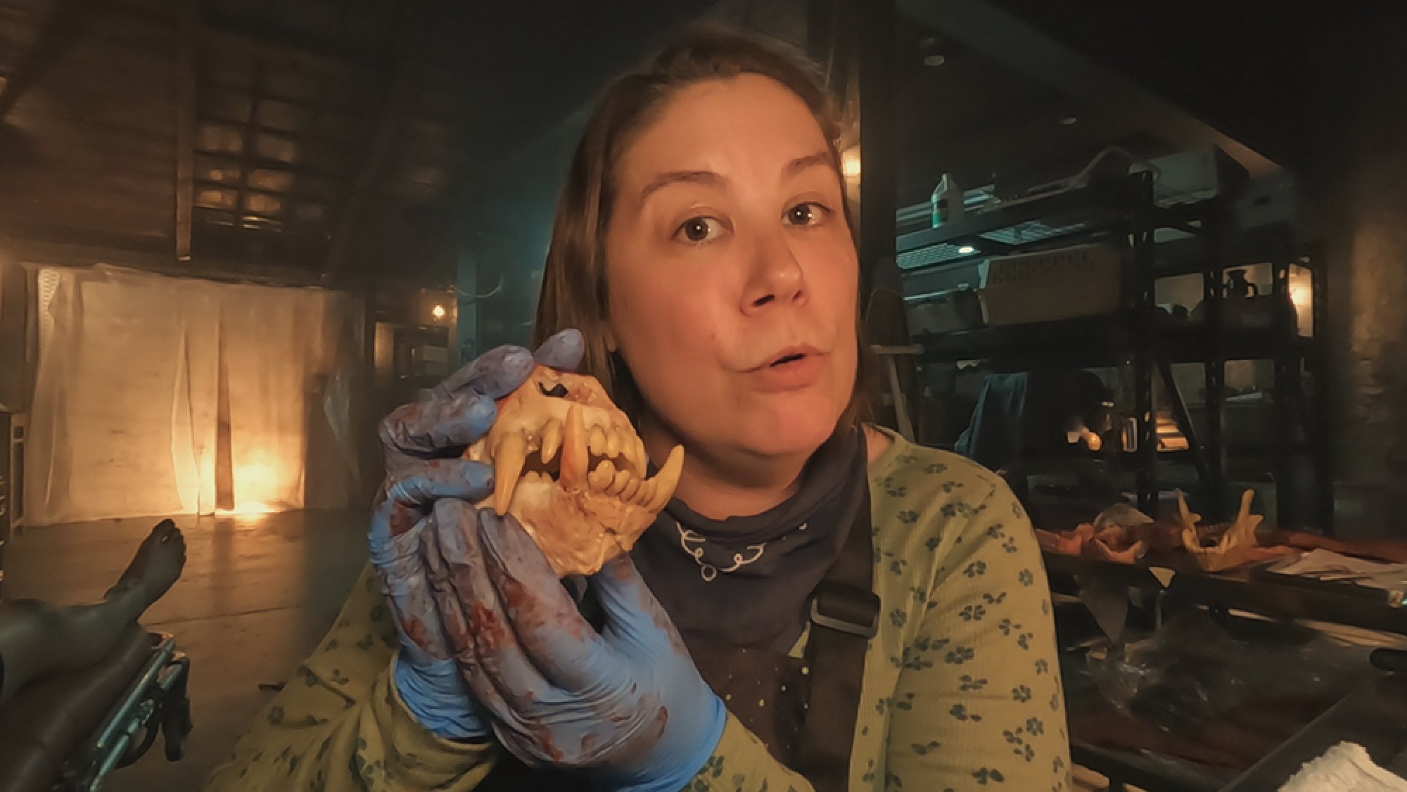 A woman stands facing the camera, holding the jaw bones of a dog.