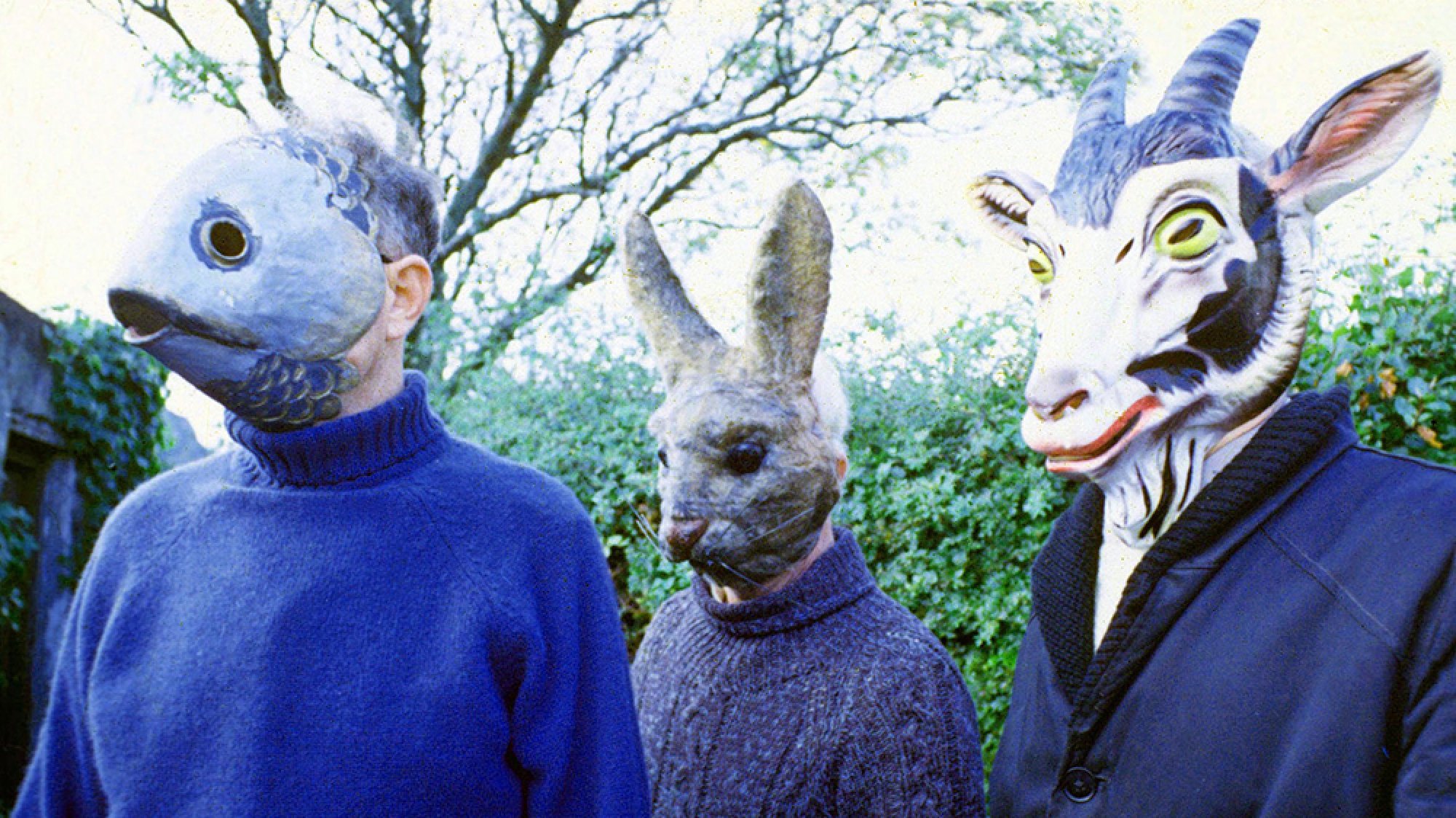 Three people stand outside wearing animal masks.