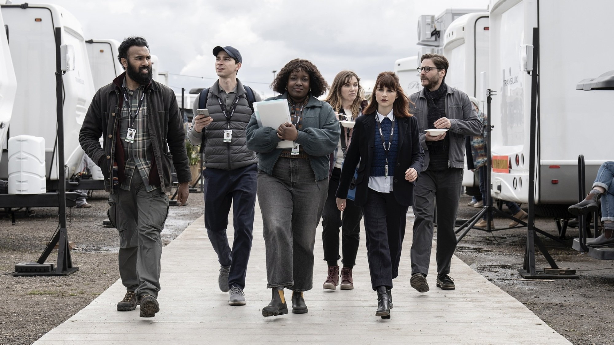 A film crew walks through a row of trailers on their way to set.