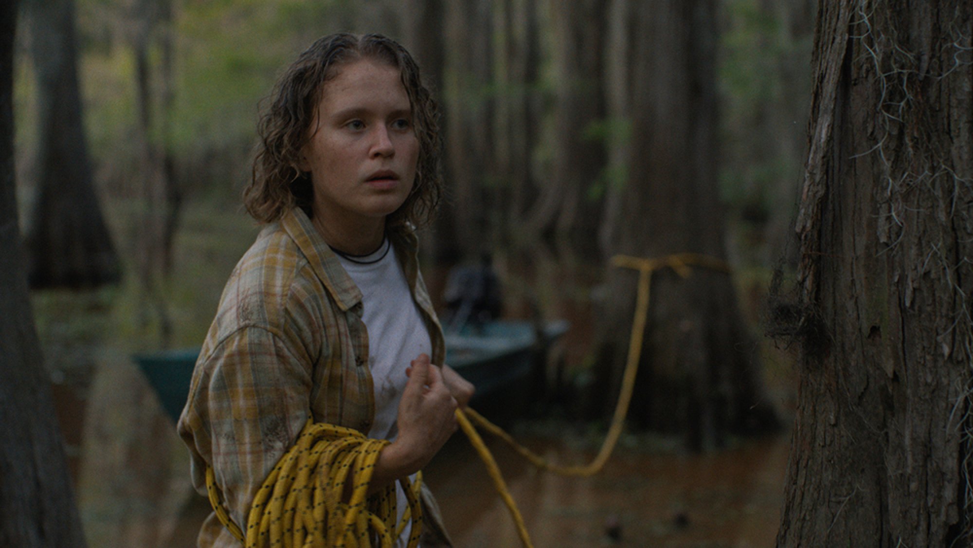 A woman follows a yellow rope tied around a tree.