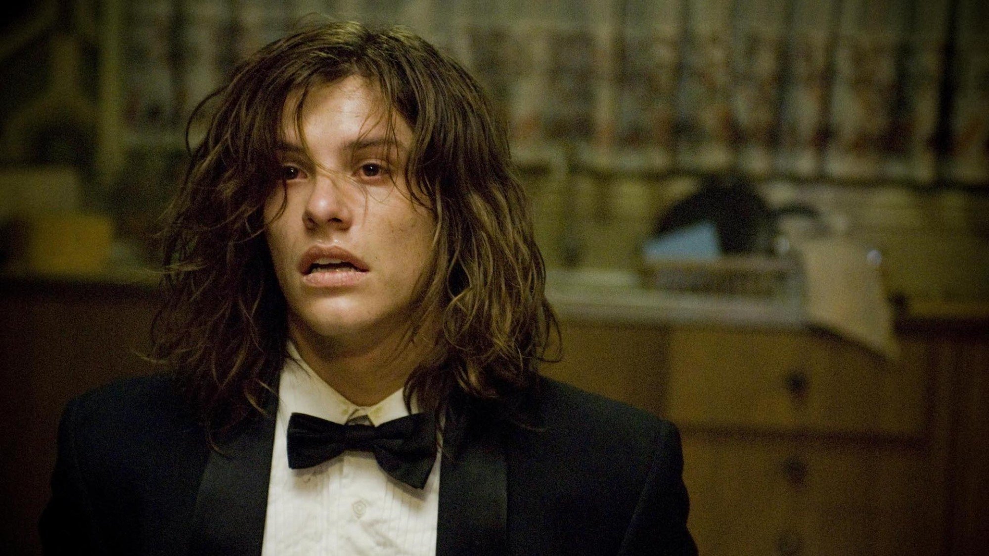 Xavier Samuel sits in a kitchen chair in a suit, looking despondent, in the film "The Loved Ones".