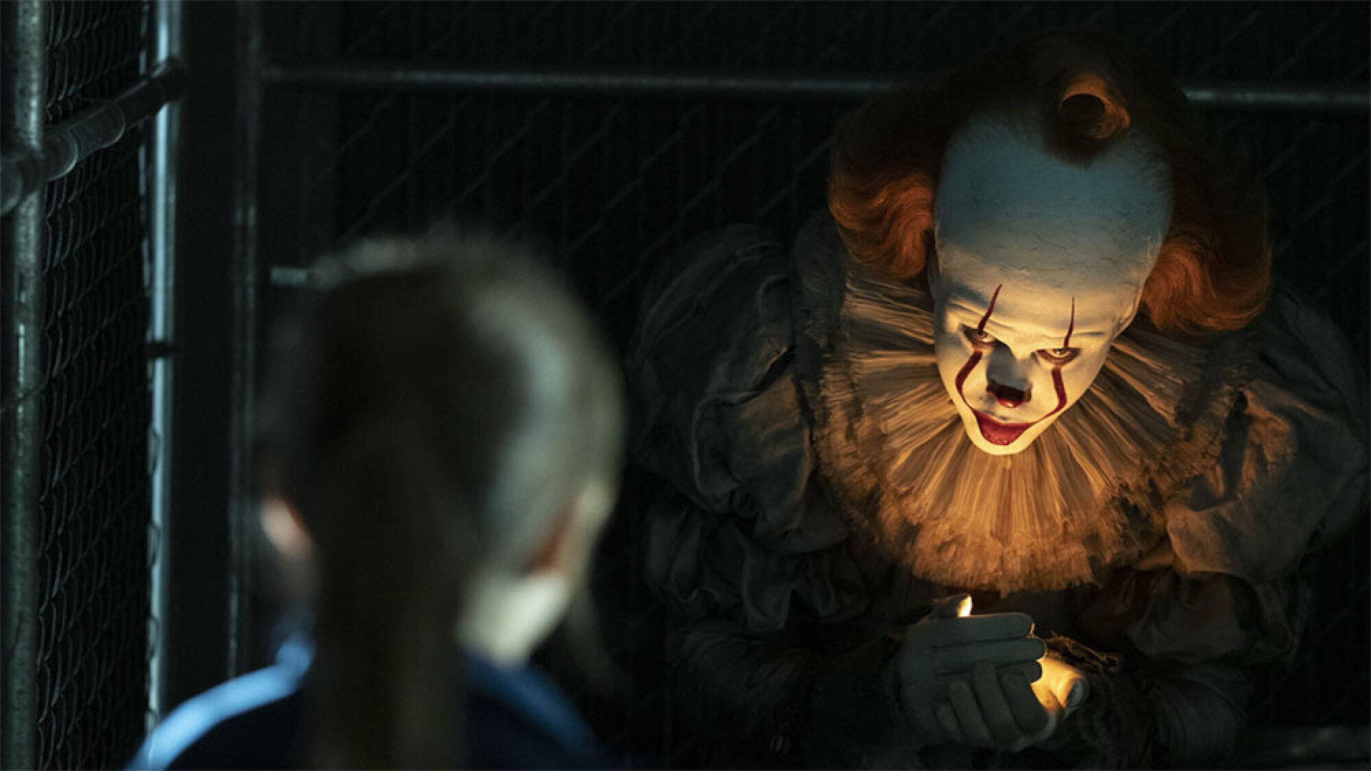 A creepy clown leers out of the darkness at a kid.