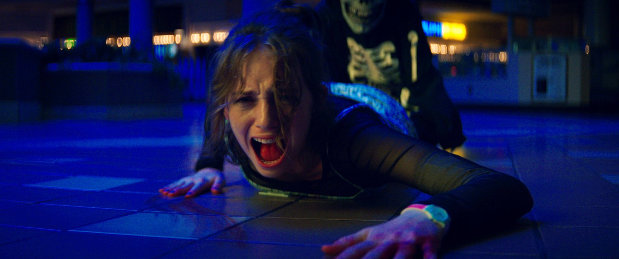 A teen girl screams while lying on the floor of a mall. 