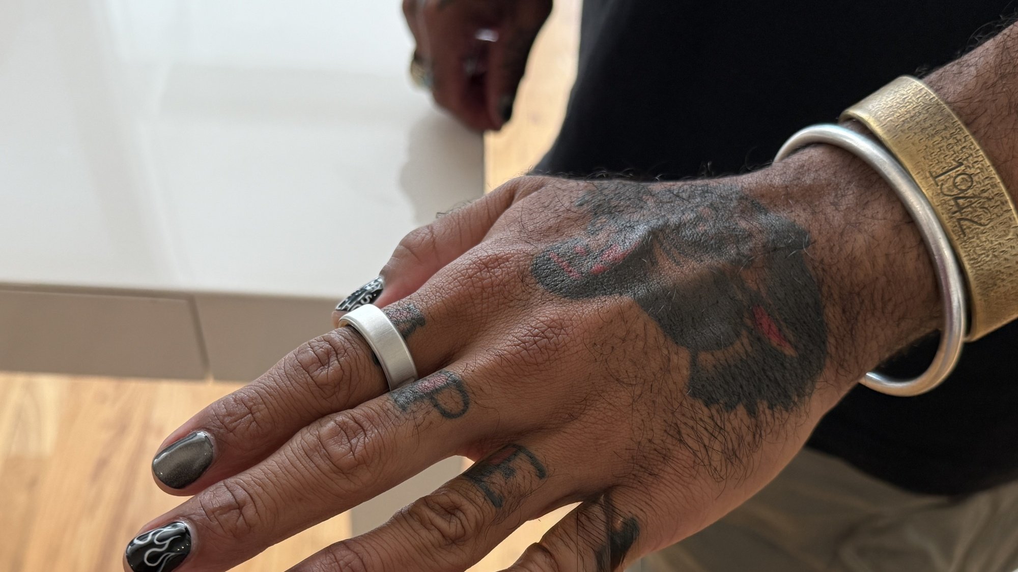 Oura Ring 4 on a man's finger with bracelets around his wrist