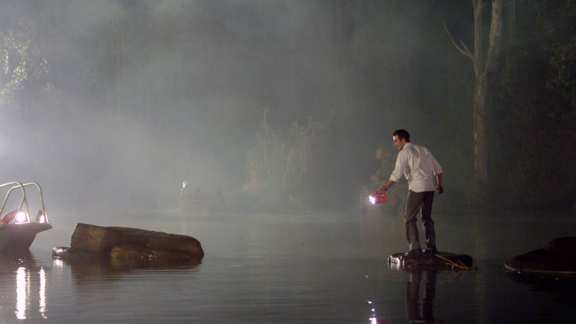 Michael Vartan stands by a river at night holding a torch in the film "Rogue".