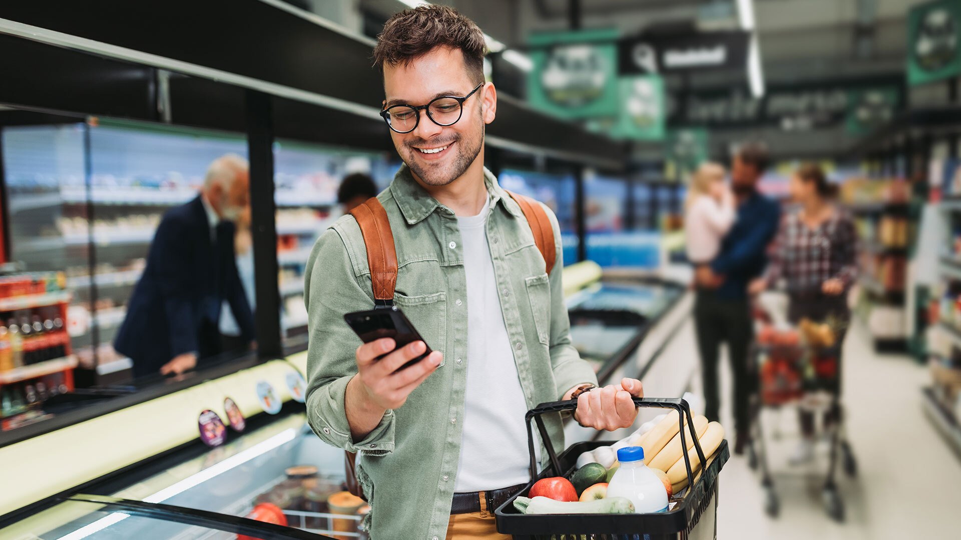 A person looking at their phone while standing in a grocery store.