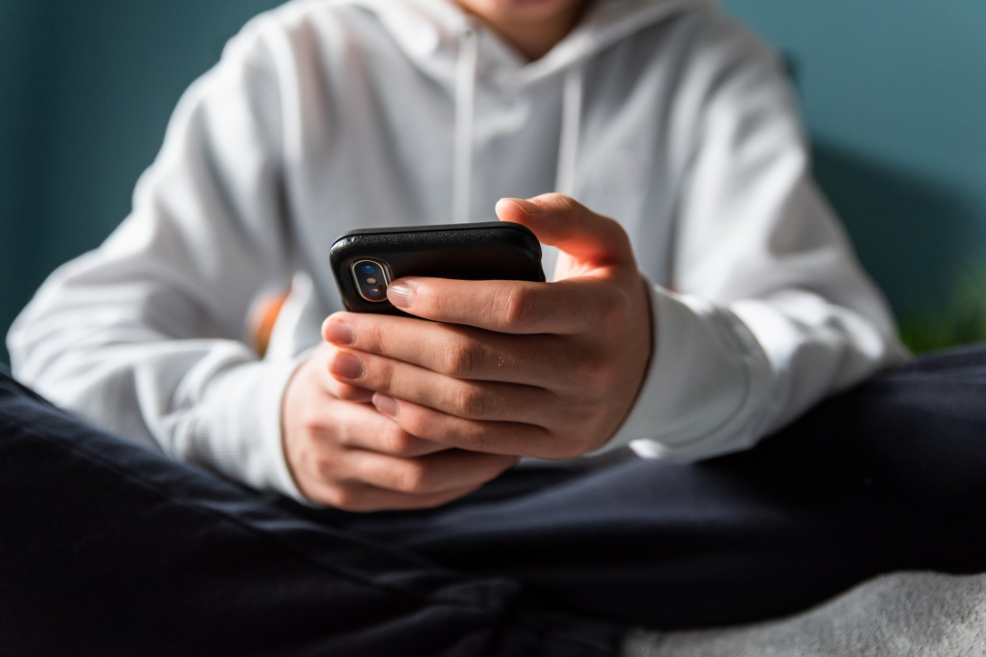 A young person holds a phone in their hands.