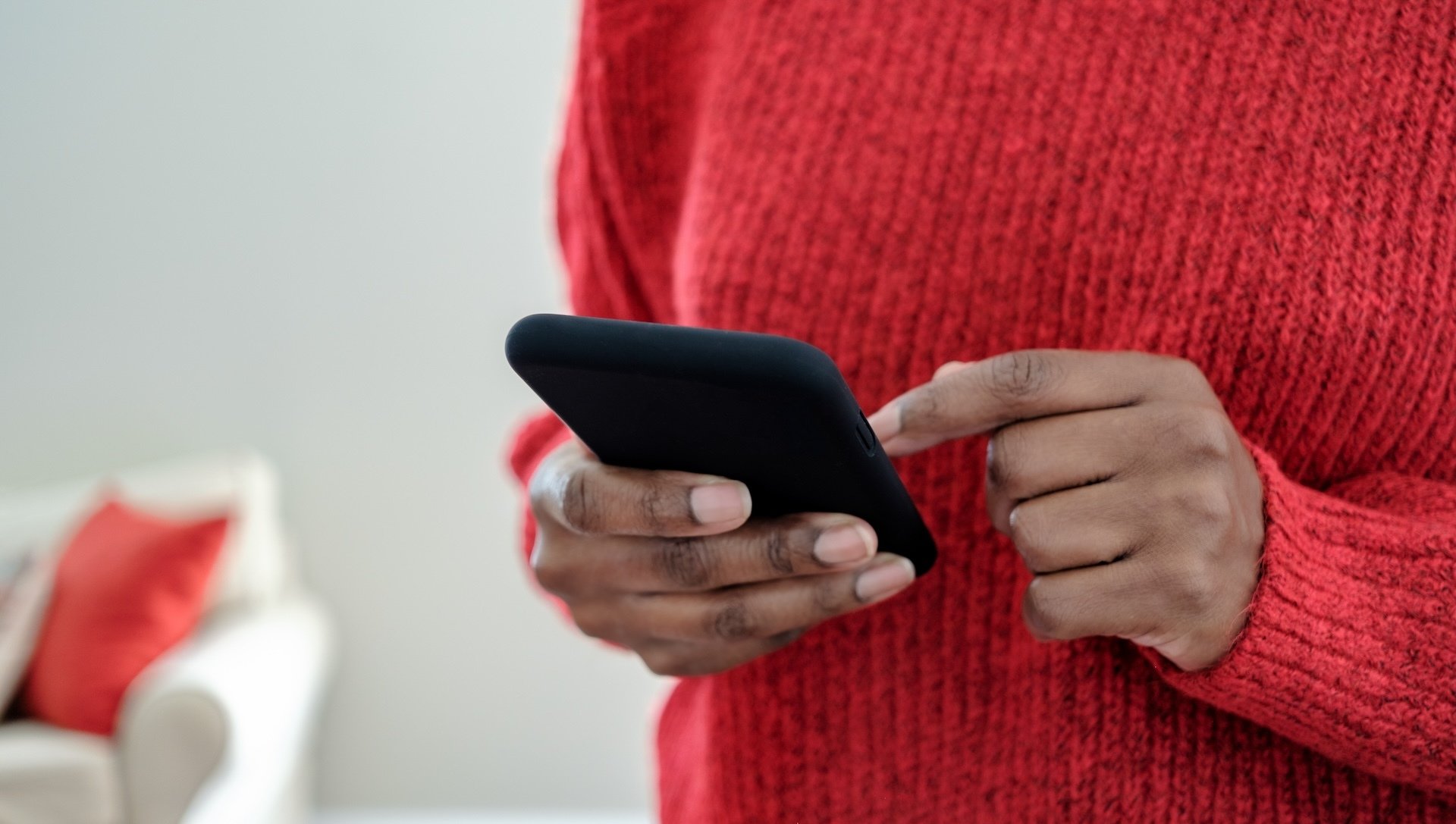 A Black person checks their smartphone.