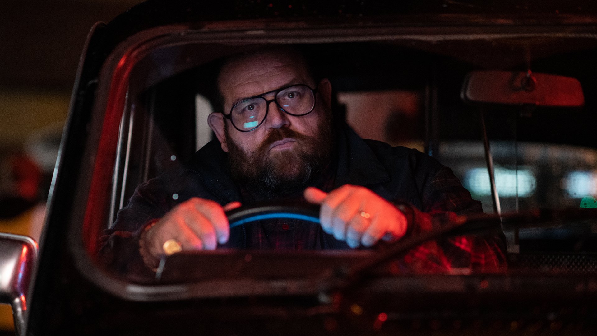 A man sits behind the wheel of a black cab.