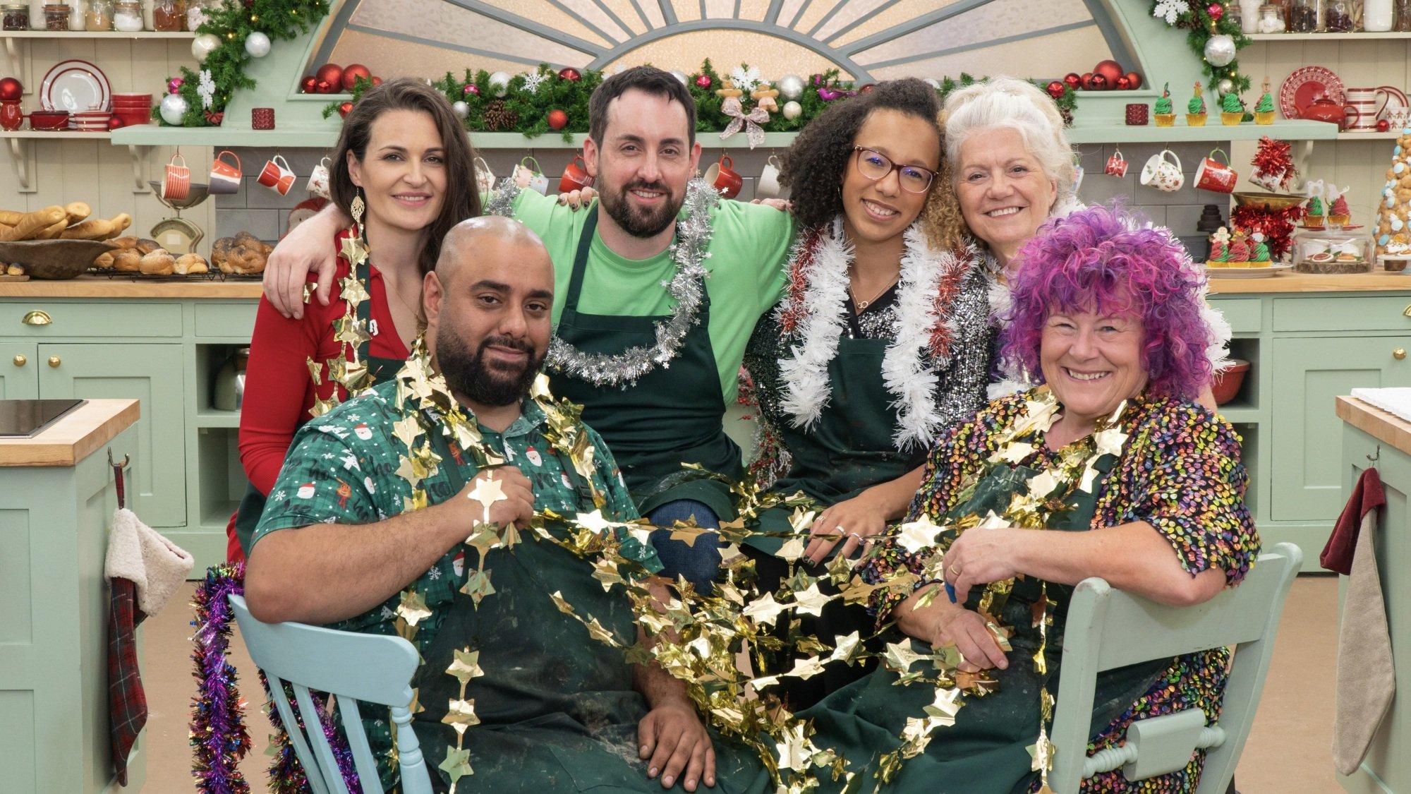 The cast of "The Great British Baking Show: Holidays" in the tent, wrapped in tinsel.